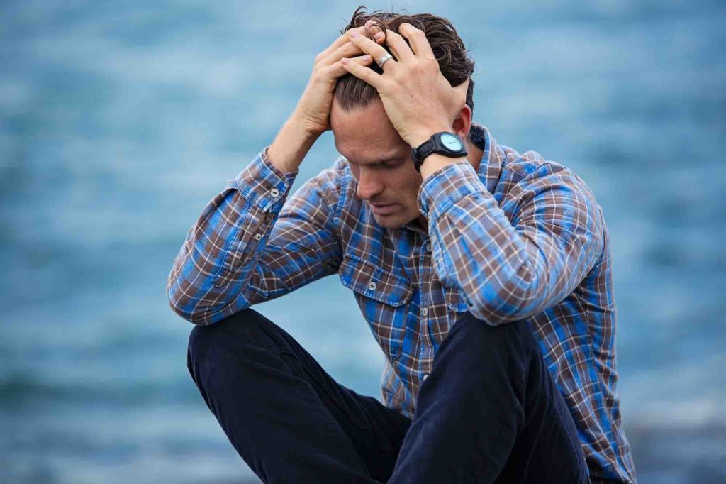 depressed man sitting on beach