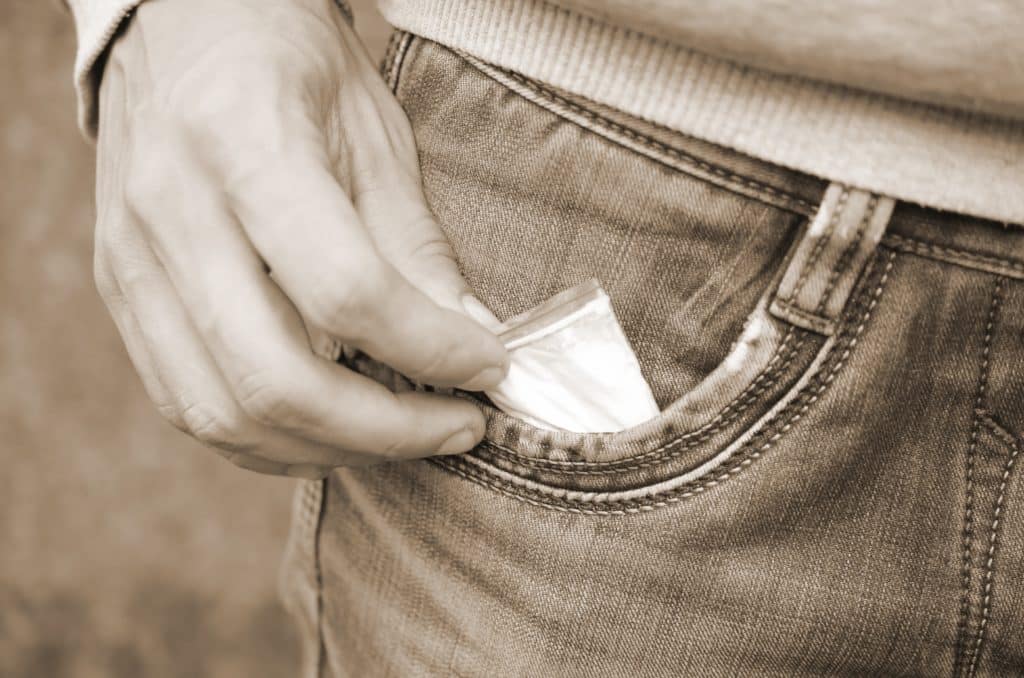 Man putting a bag of meth in his pocket